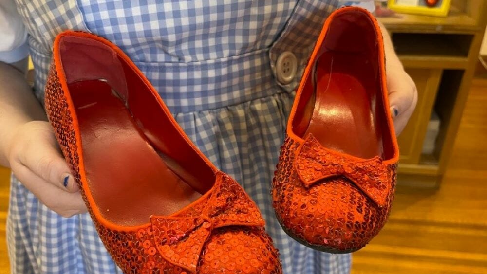 A Dorothy Gale impersonator who works at Dorothy's House in Liberal, Kansas, holds a pair of ruby slippers she wears while leading tours of the museum.
