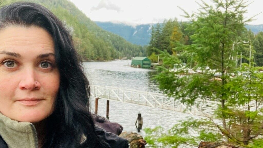 Chef Laura Comer overlooking a river in a Canadian forest.