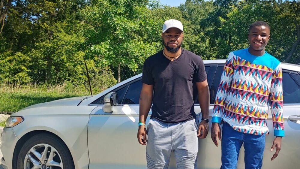 Justin Bilombele (left) and Amuri Justin (right) are stand outside of the car in Kessler Park, where Bilombele taught Justin how to drive.