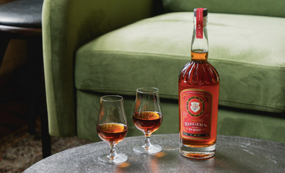 Two glasses and a bottle of J. Rieger & Co.'s Straight Rye Whiskey.