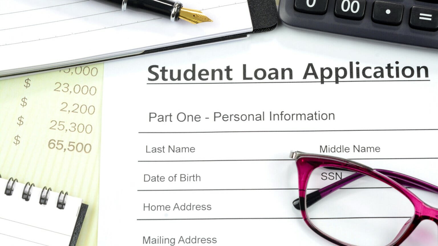 Applying for student loan. Filling up the loan form with calculator, pen, note pad on the desk