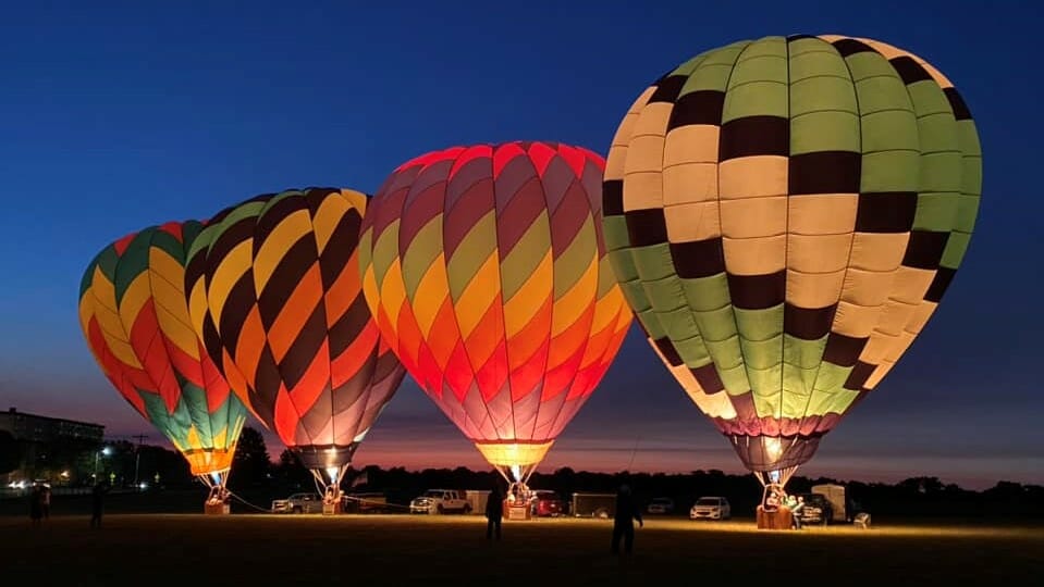 Four colorful hot air balloons lit up at night.