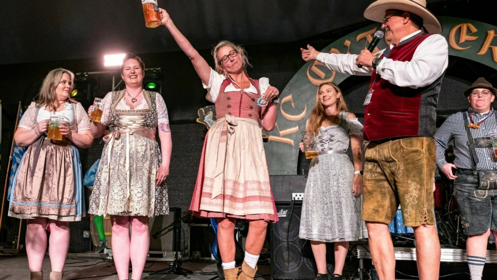 An on-stage Oktoberfest celebration with women holding steins.