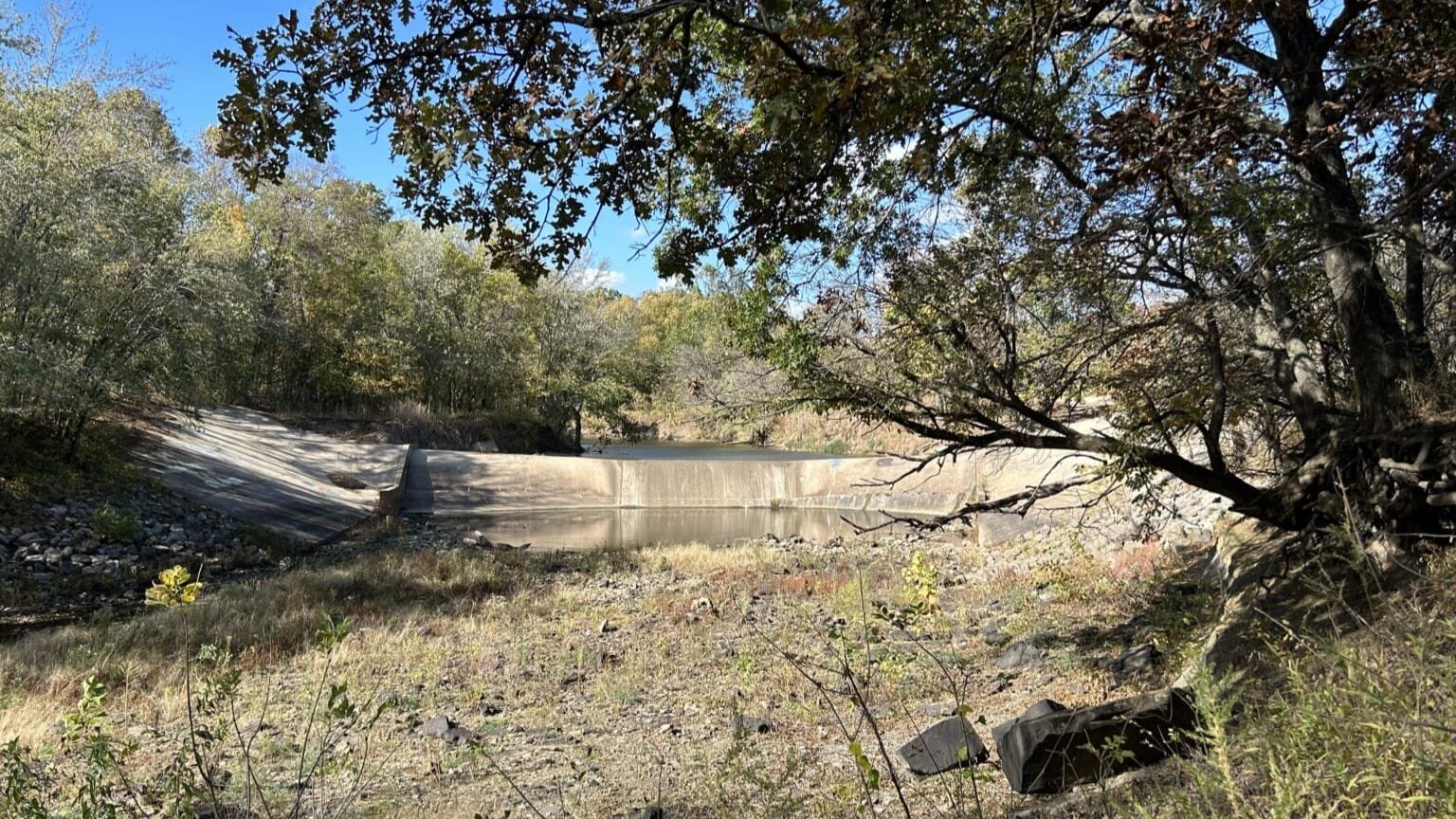 Water levels in the Little Caney River are so low that the river isn’t flowing over the dam, leaving the stream dry.