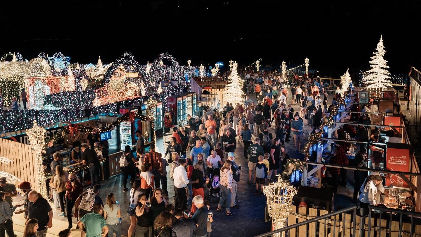 A crowd of people move through a holiday lights maze.