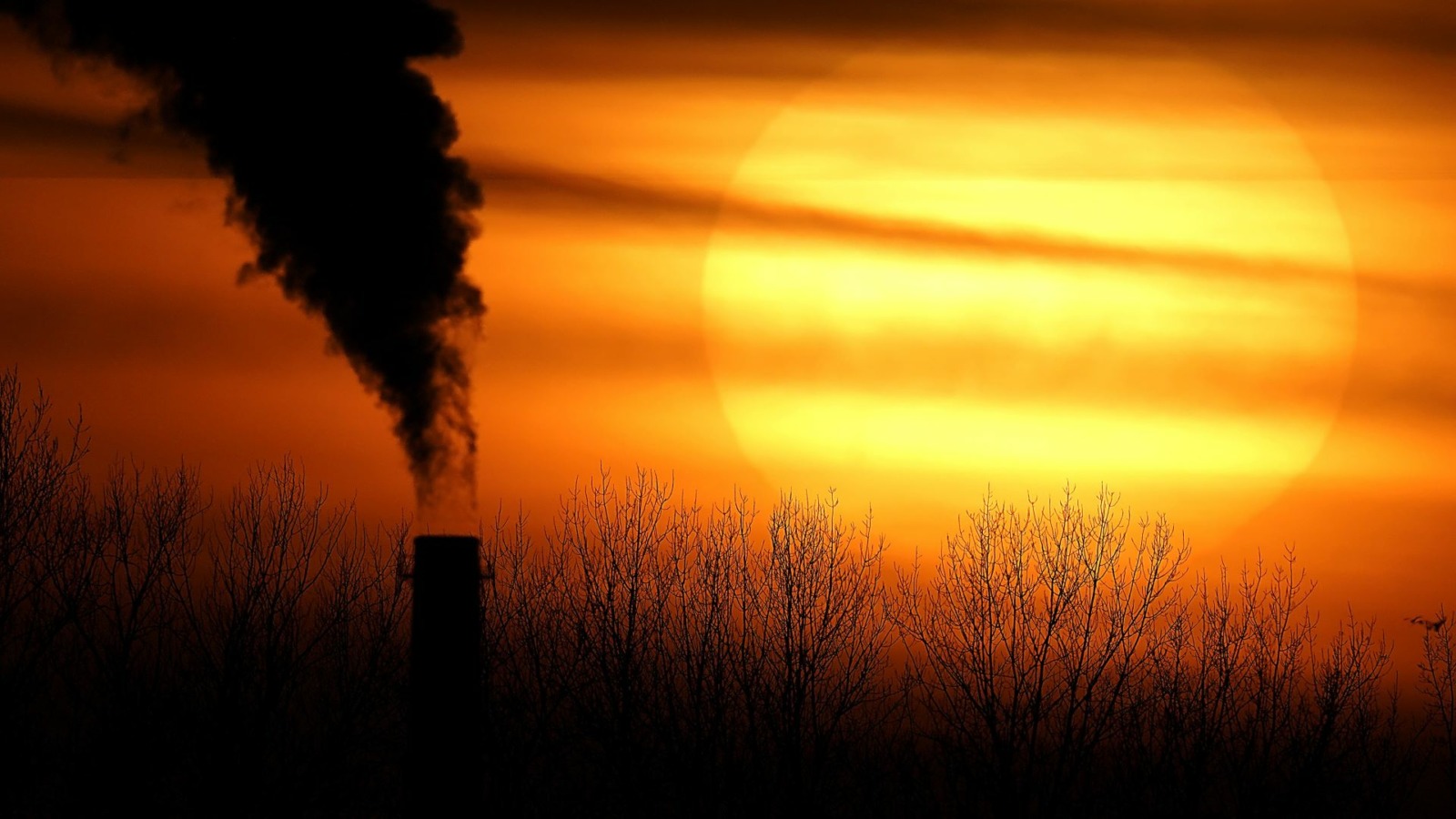 In this Feb. 1, 2021, a smokestack from Evergy's Hawthorn coal-fired power plant is silhouetted against the setting sun in Kansas City.