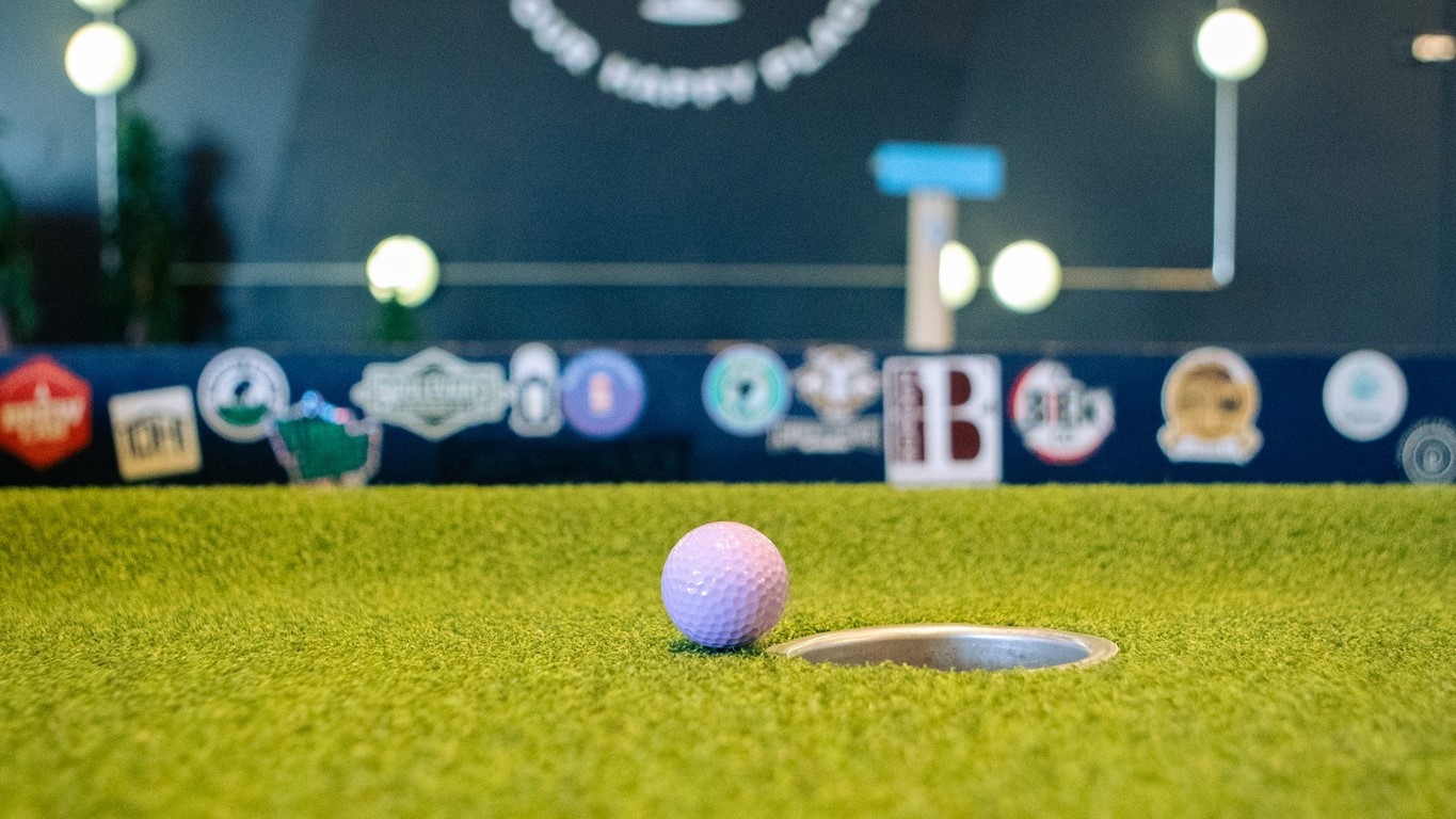 A golf ball near a hole on a mini golf course