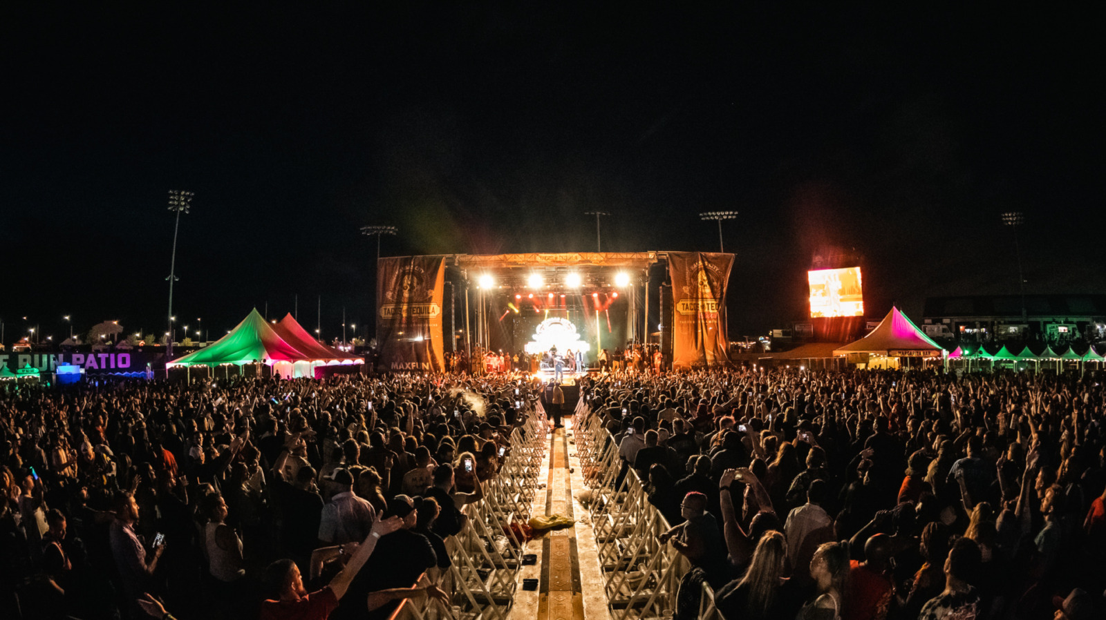 A stage lit up at night with a large crowd.