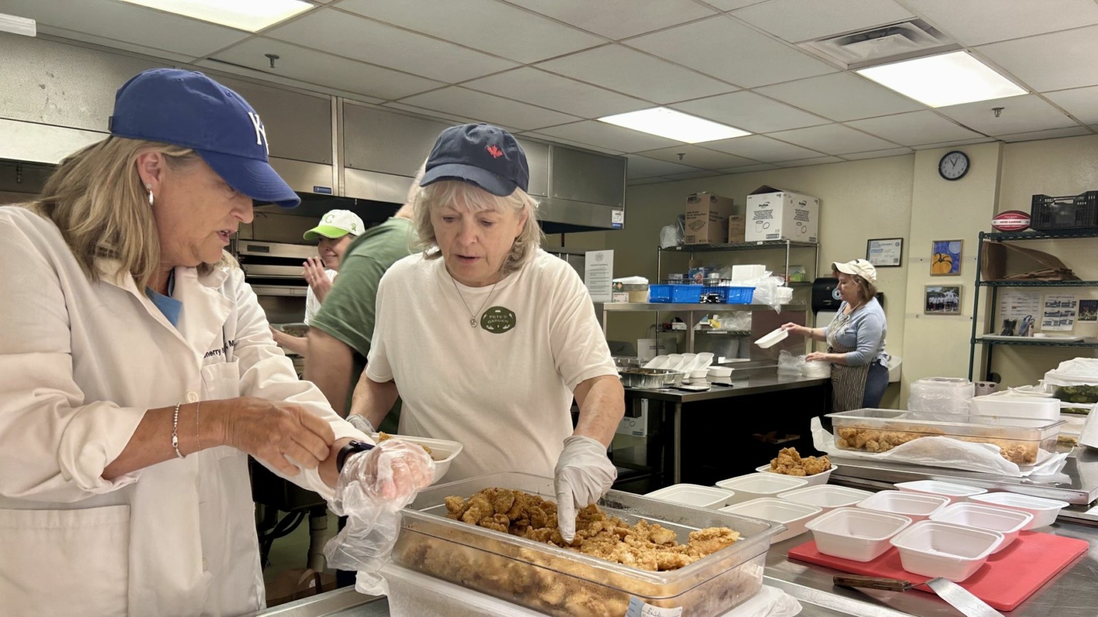 Volunteers scoop meat into containers in the kitchen of Pete’s Garden.