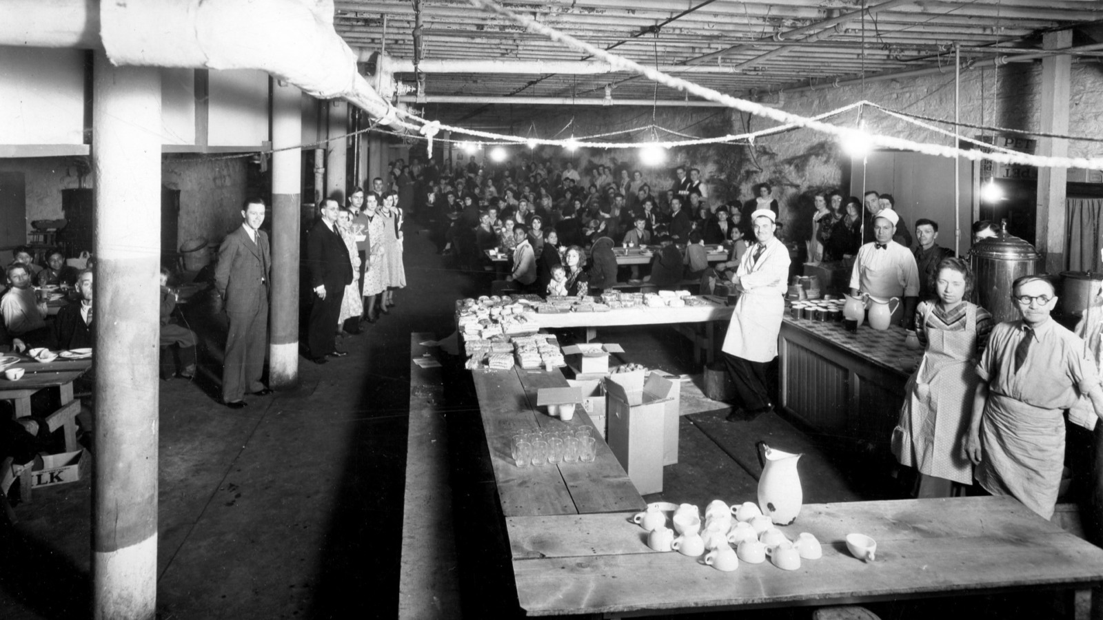 A photo from a 1930s mission Christmas season meal includes David Bulkley, in a dark suit at left and - holding a guest’s child at the nearby table - his daughter Ruth.