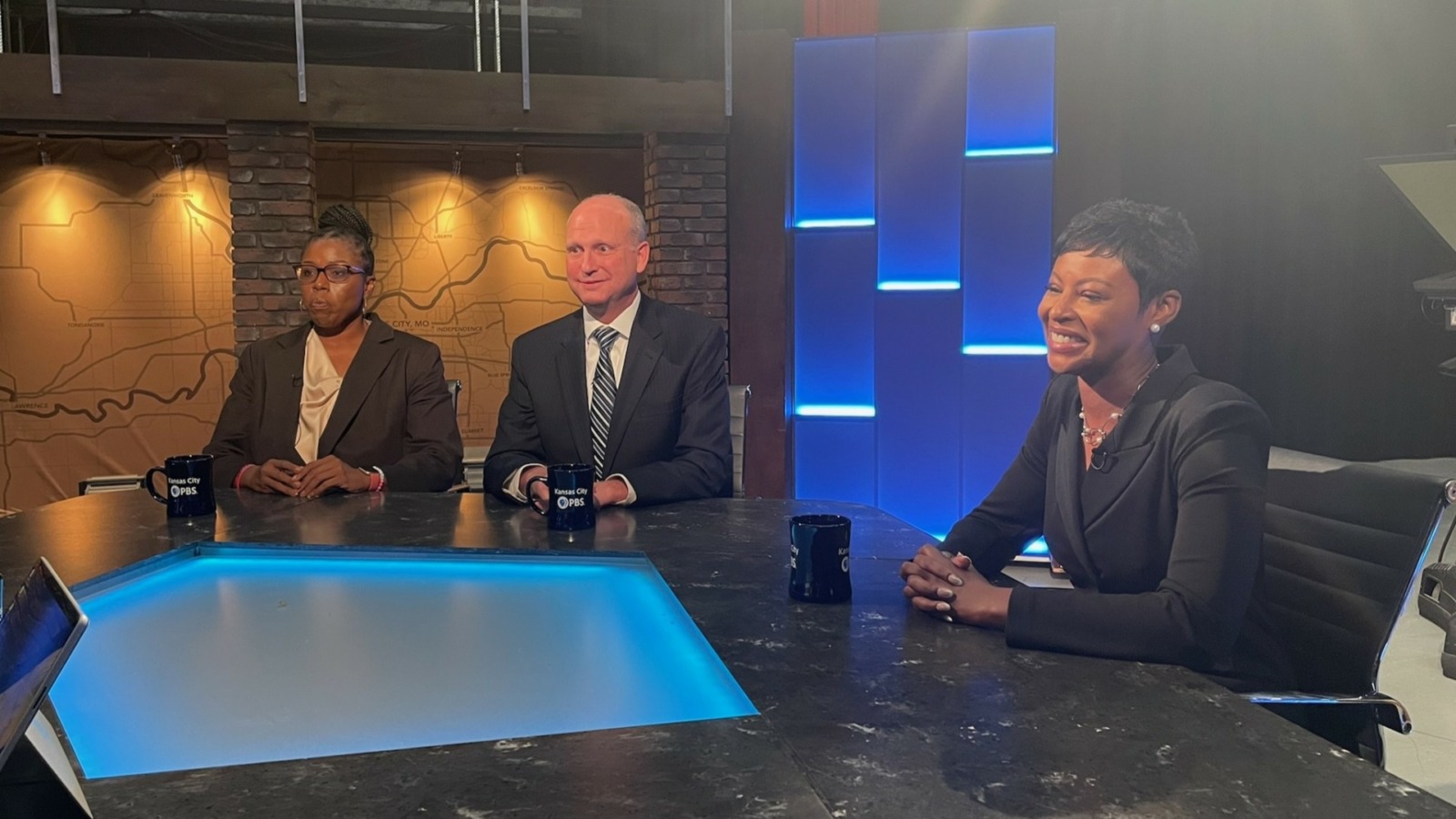 Three people seated at a table. Week in Review set.