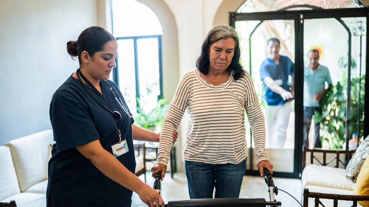 A nurse assists a woman using a walker.