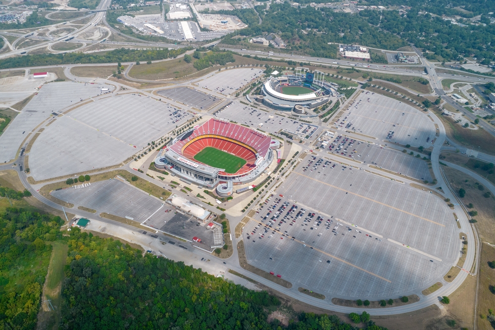 An aerial view of two stadiums with a large expanse of parking lot surroum.nding the