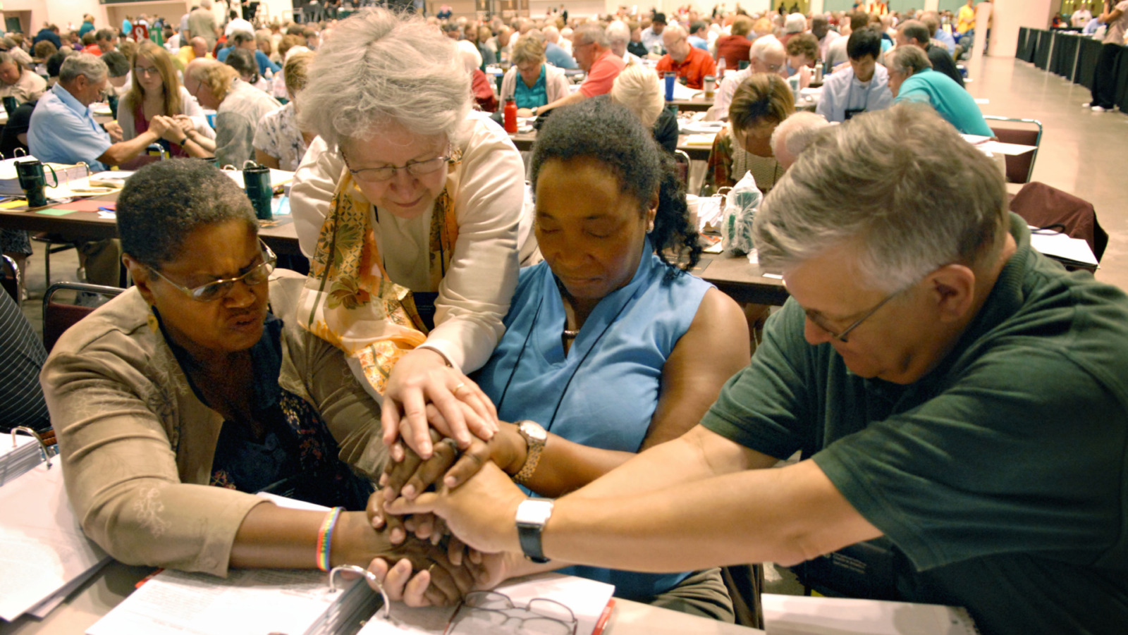 Evangelical Lutheran Church of America voting members, left to right, Orinda Hawkins-Brinkley, Diane Yeager. Marj Ellis and Steven Schnittke, along with other members of the ELCA, stop for a moment of prayer Friday morning Aug. 21, 2009 during their assembly at the Minneapolis Convention Center in Minneapolis. More than 1,000 members debated and voted on whether to allow gay and lesbian clergy to serve while be in committed same-sex relationships. (AP Photo/Dawn VIllella)