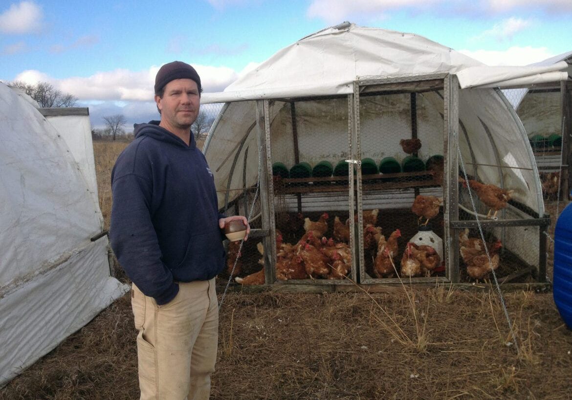 a man standing my a chicken pen.