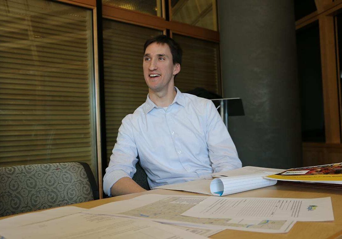 Picture of Mike English sitting at conference table with papers sprawled in front of him