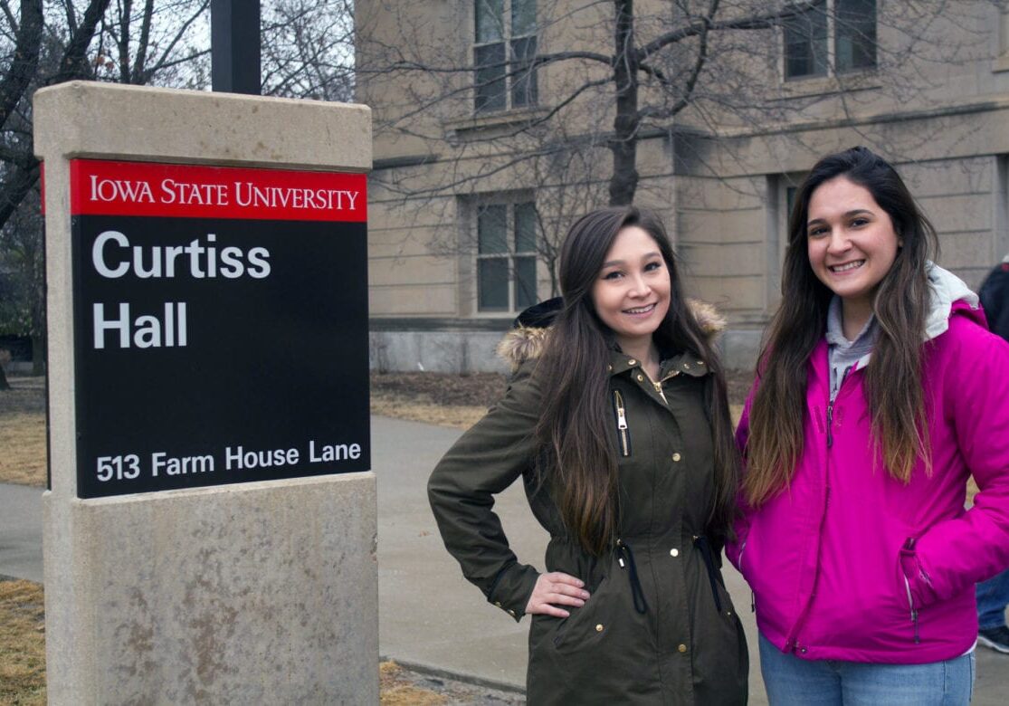 Two women standing on a college campus.