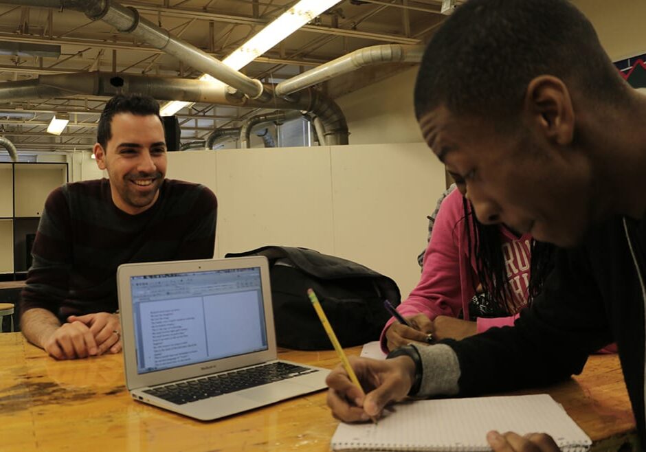 Photo of teacher and student with laptop sitting at table.