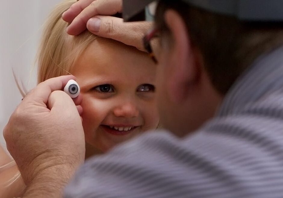 Ocularist fitting a young girl with a prosthetic eye