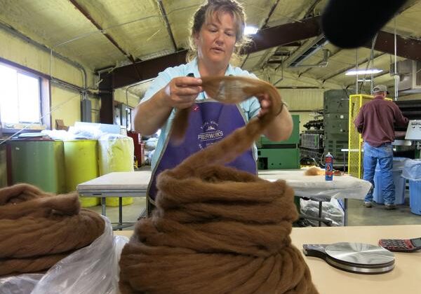 Image of yarn maker handling wool during yarn-making process