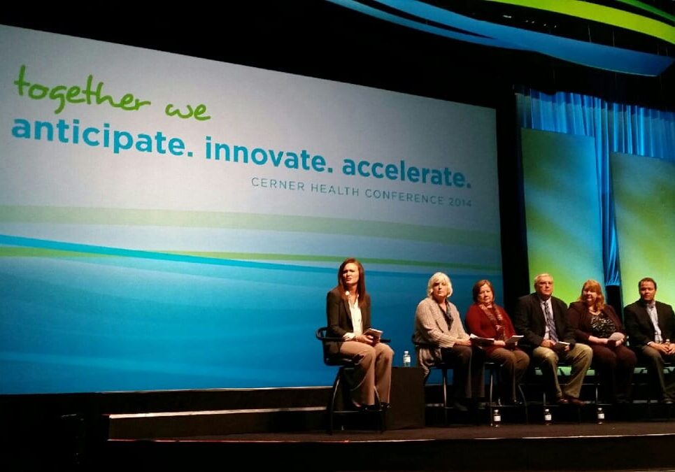 Photo of 6 panelists on stage with Cerner Health Conference logo on large screen