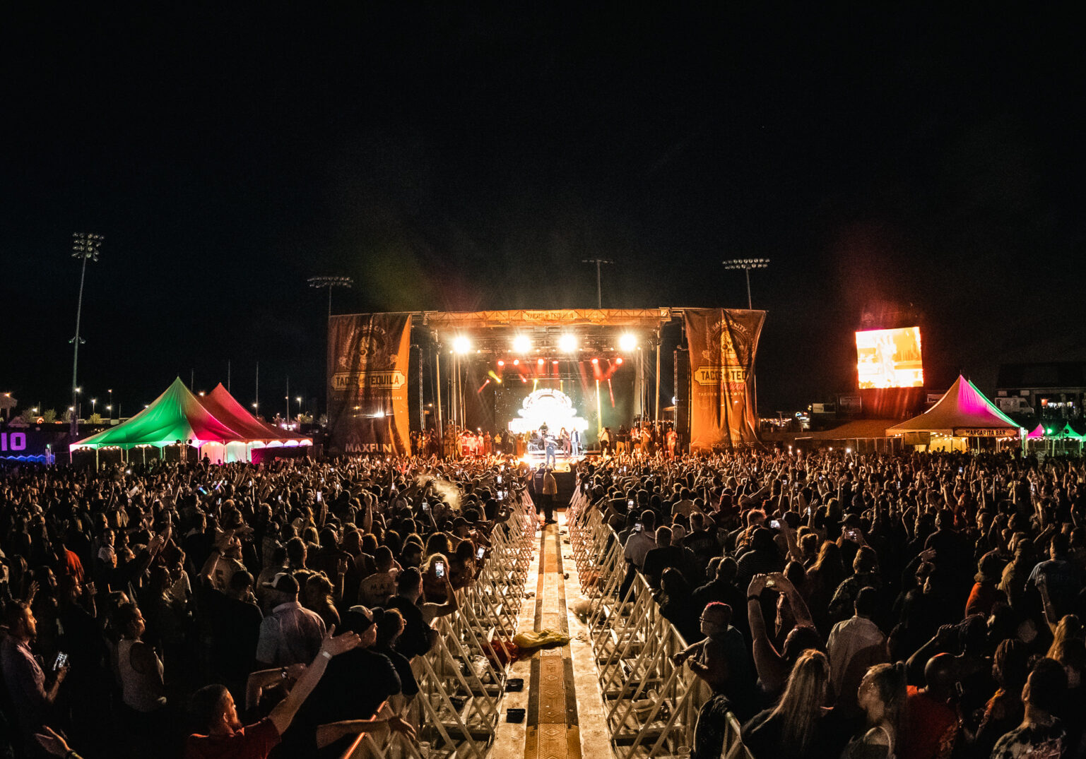 A stage lit up at night with a large crowd.