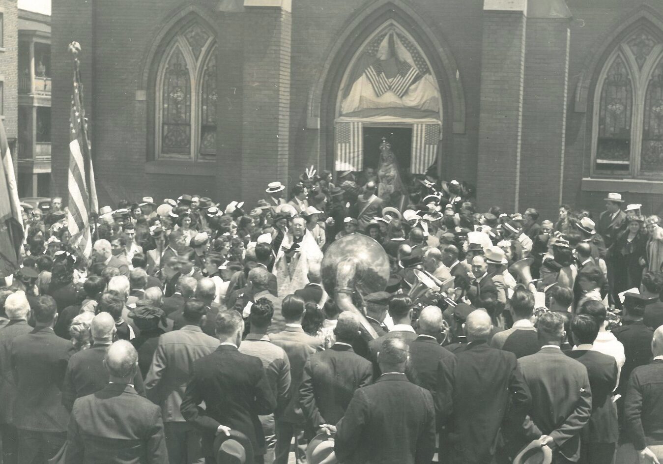 A crowd gathers around a priest outside of Holy Rosary Church.
