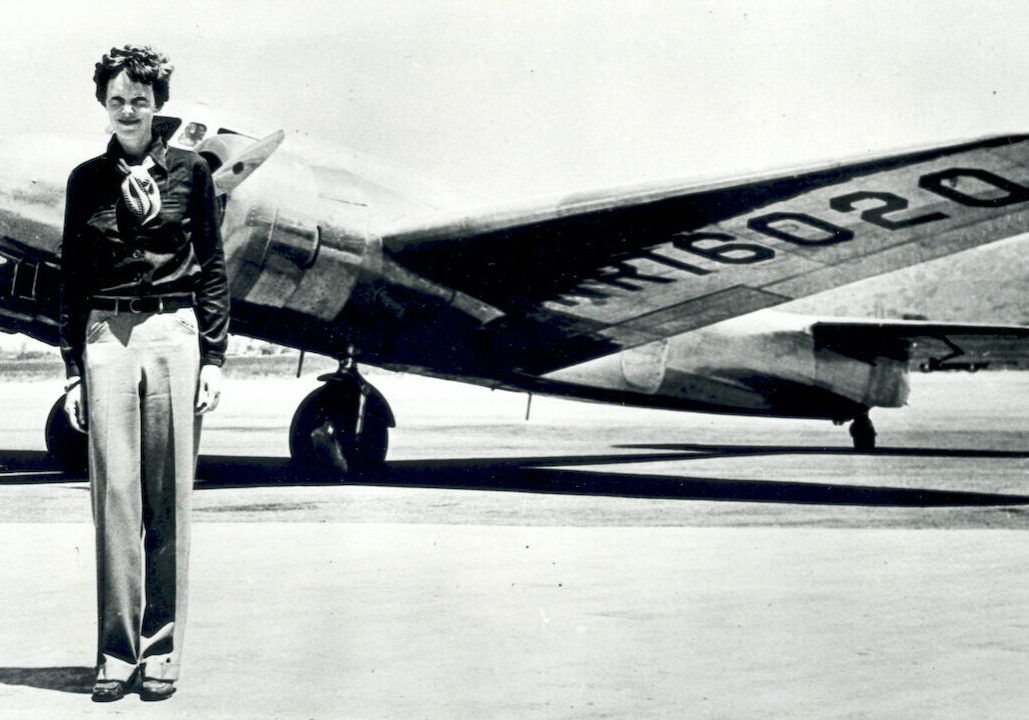 Vintage photo shows Amelia Earhart in front of a plane.