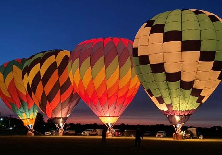 Four colorful hot air balloons lit up at night.