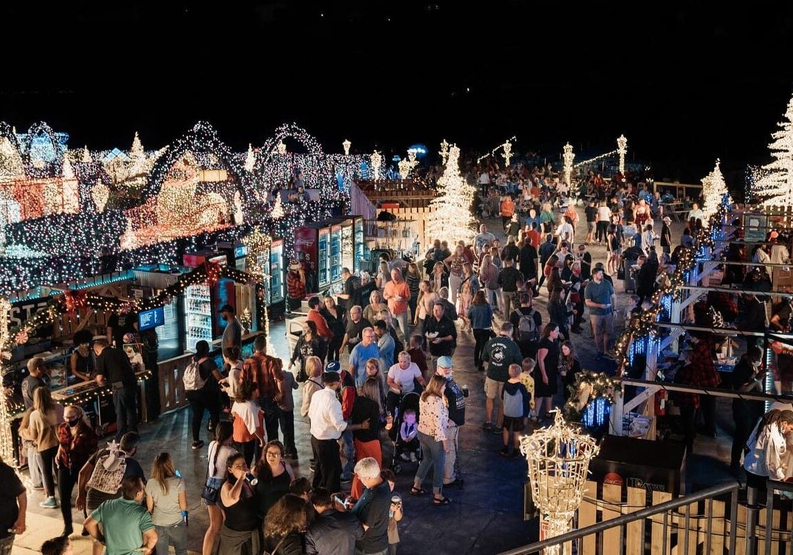 A crowd of people move through a holiday lights maze.