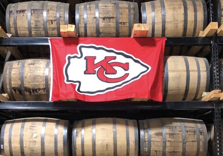 A Chiefs flag hangs on barrels of whiskey at J. Rieger & Co. Distillery