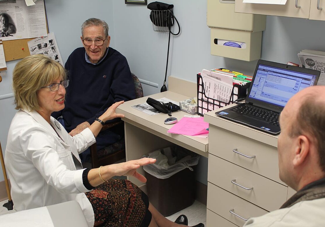 Marsha Stiefel, a nurse practitioner and diabetes educator, consulted recently with 92-year-old John A. Smith (top)and his son, Daniel Smith, at Encompass Medical Group in Lenexa. Encompass is working with the federal government to reduce costs among Medicare patients. Photo by 