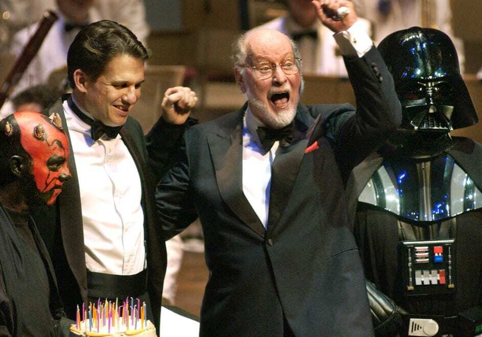 Composer and conductor John Williams, third from left, raises his arm in celebration as Boston Pops conductor Keith Lockhart, second from left, and Star Wars characters Darth Maul, left, and Darth Vader, right, look on. (Photo: Steven Senne | AP File)