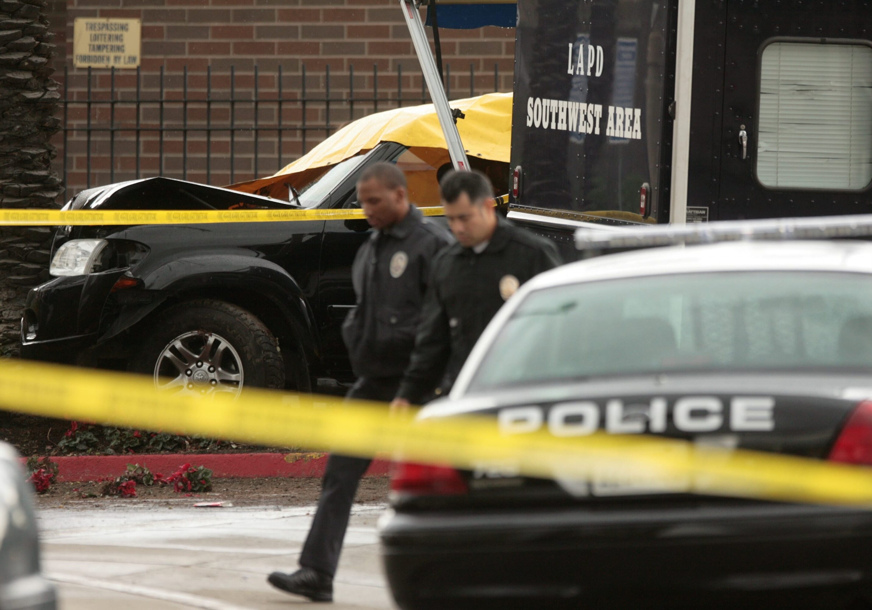 Police walk past a crashed vehicle outside the Baldwin Hills Crenshaw Plaza mall in Los Angeles, Tuesday, Jan. 22, 2008. Bank robbery suspects threw handfuls of cash from a speeding car before crashing outside a Los Angeles mall. One person was taken into custody Tuesday after a pursuit that topped 100 mph and moved through two counties. (AP Photo/Damian Dovarganes)