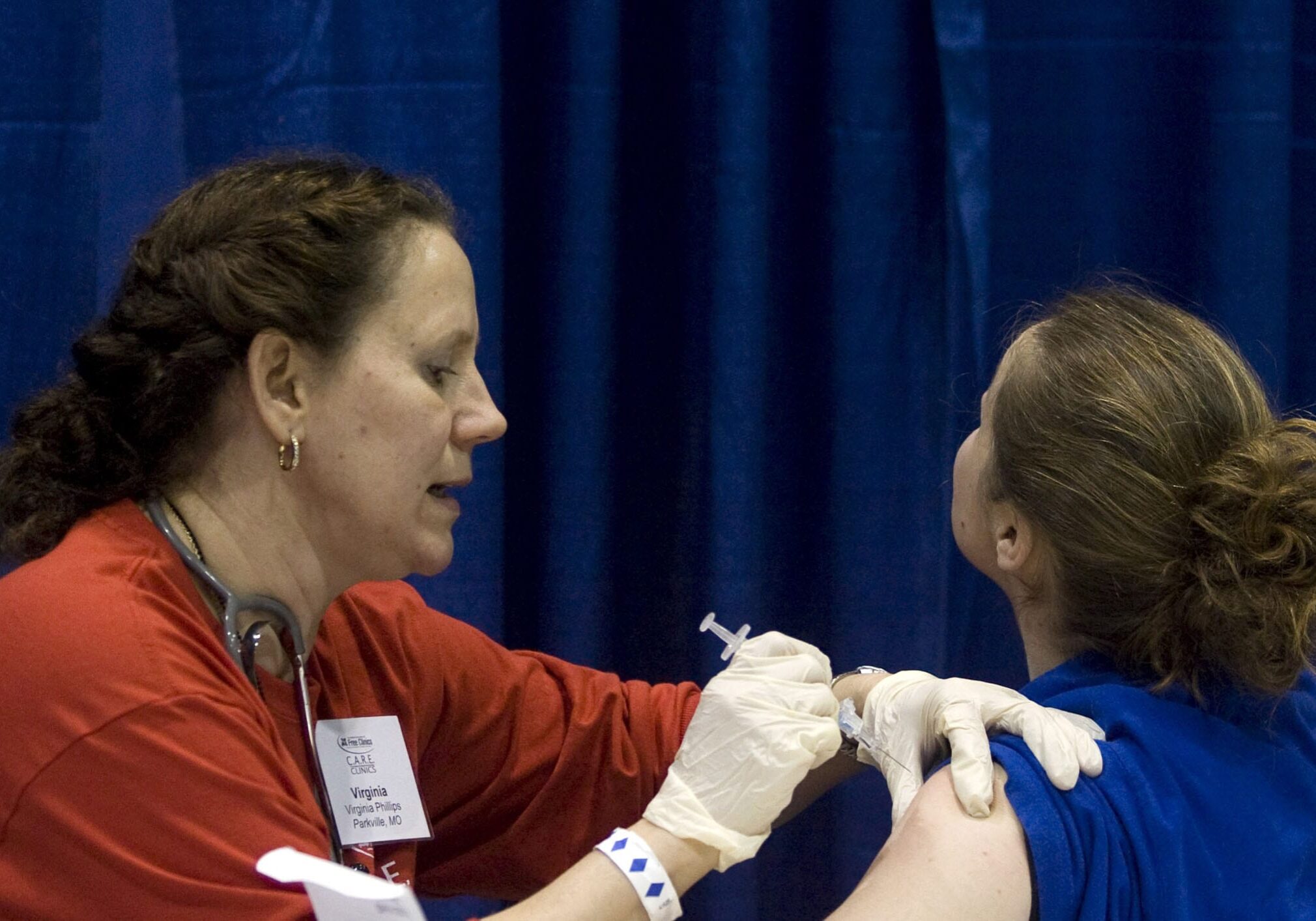 Volunteer nurse Virginia Phillips, left, administers a H1N1 flu shot to Crystal Sickles at a free clinic at Bartle Hall Wednesday, Dec. 9, 2009, in Kansas City, Mo. Sickles was one of about 1,000 people who showed up to the free clinic sponsored by the nonprofit National Association of Free Clinics.  (AP Photo/Ed Zurga)