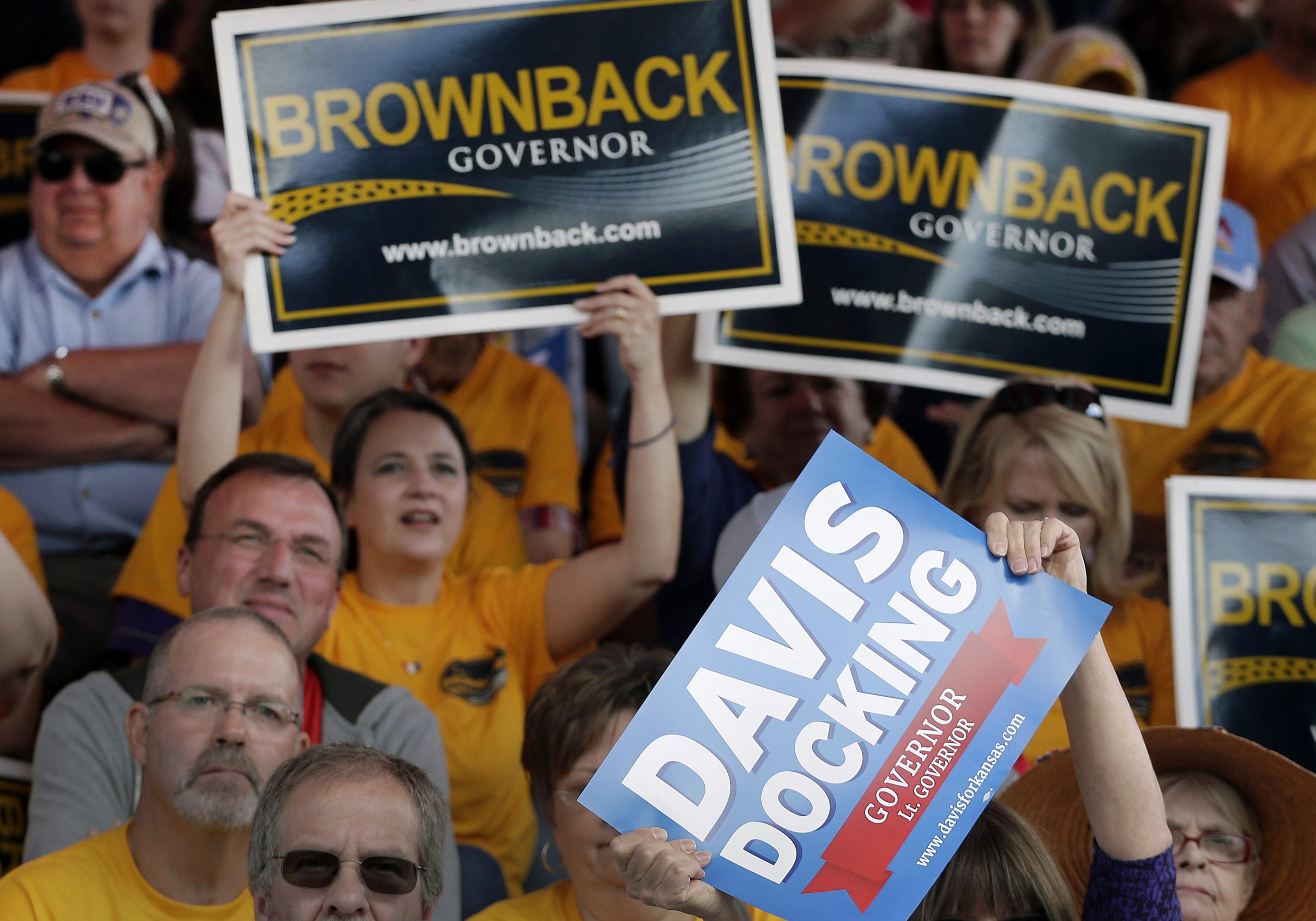 Photo of crowd holding Brownback and Davis/Docking signs at debate