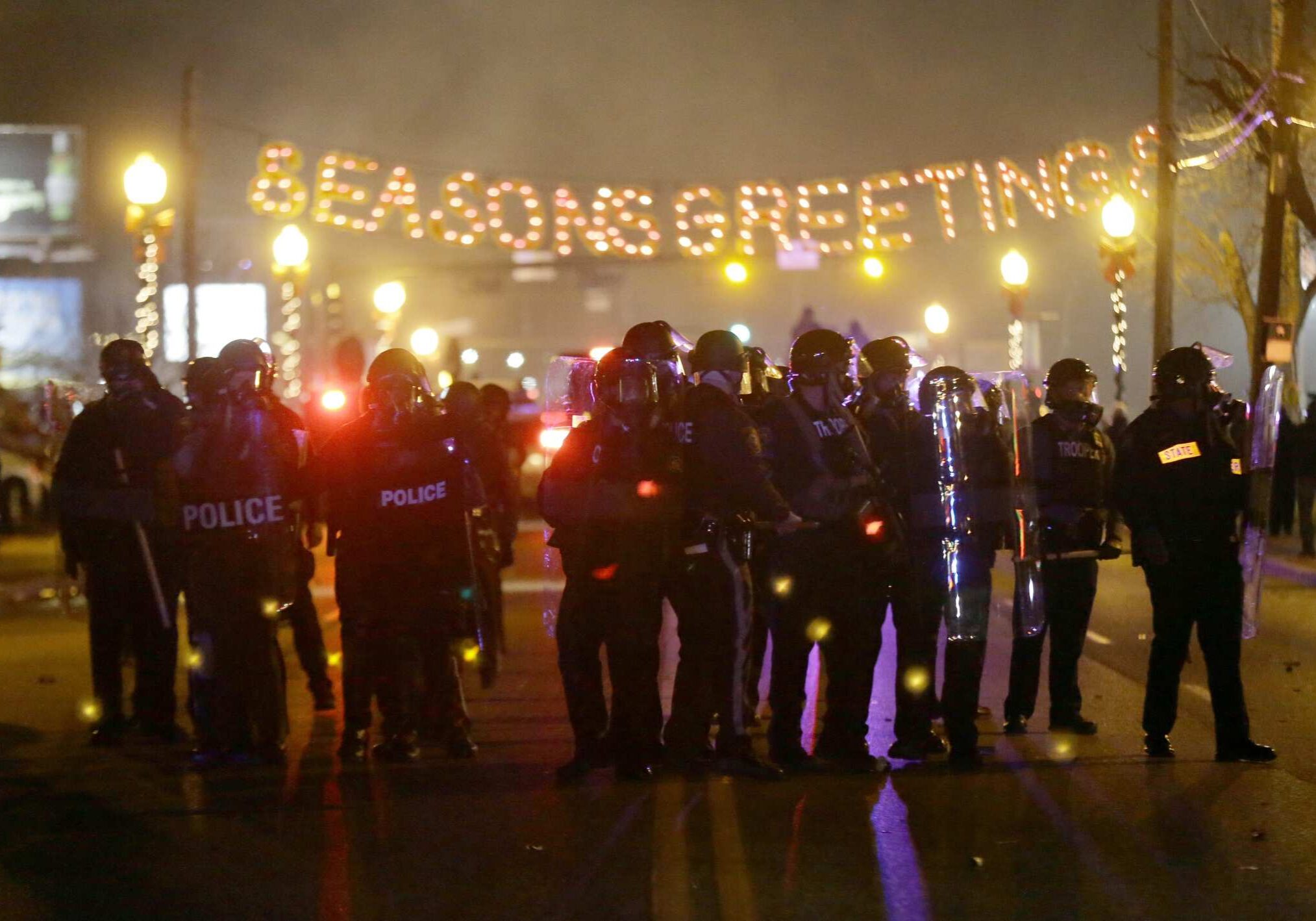 Police gather on the street as protesters react after the announcement of the grand jury decision Monday, Nov. 24, 2014, in Ferguson, Mo. A grand jury has decided not to indict Ferguson police officer Darren Wilson in the death of Michael Brown, the unarmed, black 18-year-old whose fatal shooting sparked sometimes violent protests. (AP Photo/Charlie Riedel)