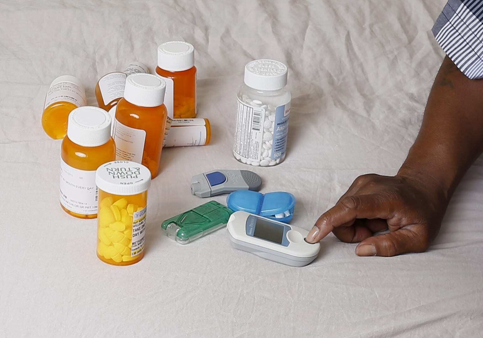 In this Monday, July 13, 2015 photo Earl Charles Williams Sr., 59, sits next to some of the medication he must take for his diabetes in his Chicago home. Williams was uninsured for about a year before a county-run clinic helped him sign up for care under the Affordable Care Act.  More than a dozen states that opted to expand Medicaid under the Affordable Care Act have seen enrollments surge way beyond projections, raising concerns that the added costs will strain their budgets when federal aid is scaled back starting in two years.   (AP Photo/Christian K. Lee)