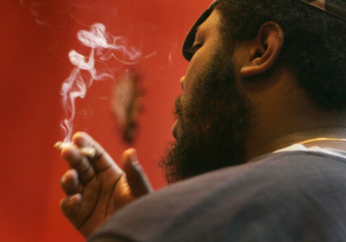 FILE - In this Jan. 23, 2008, file photo, Barrington Lloyd smokes a cigarette at a bar in St. Louis. Missouri's extraordinarily low tobacco tax will rise if at least one of two ballot measures passes in November 2016. (AP Photo/Jeff Roberson, File)