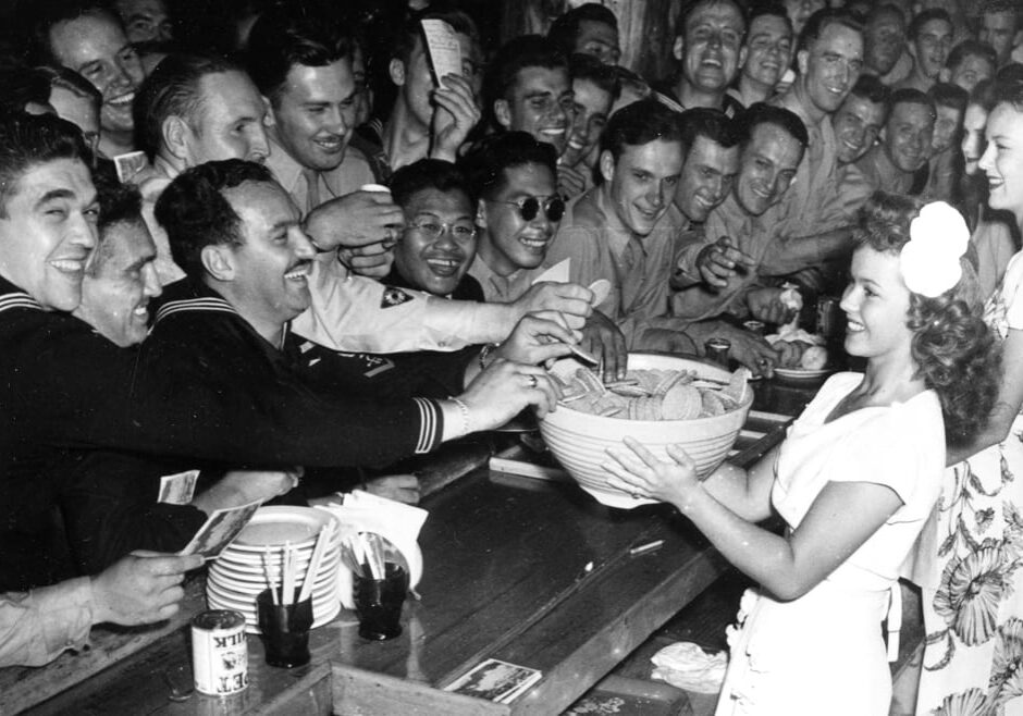 A young actress serves cookies to WWII Servicemen