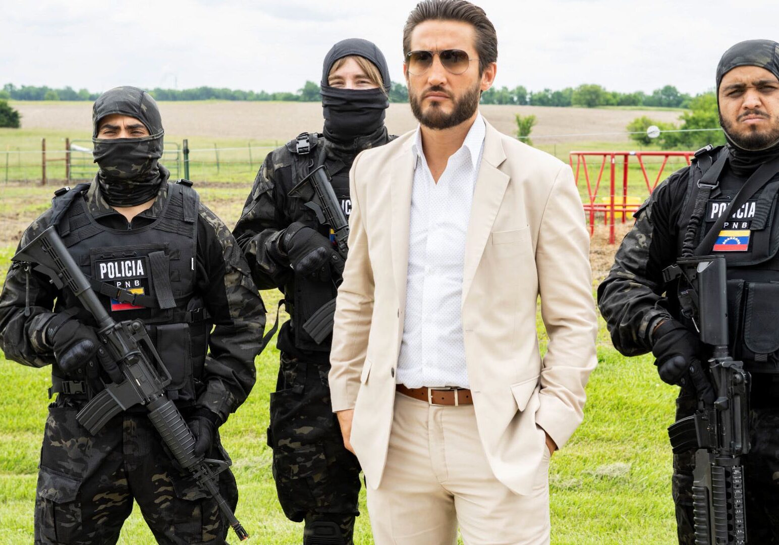 A scene from the film "The Unexpected" depicting a man in a white suit accompanied by three men in combat gear carrying weapons.