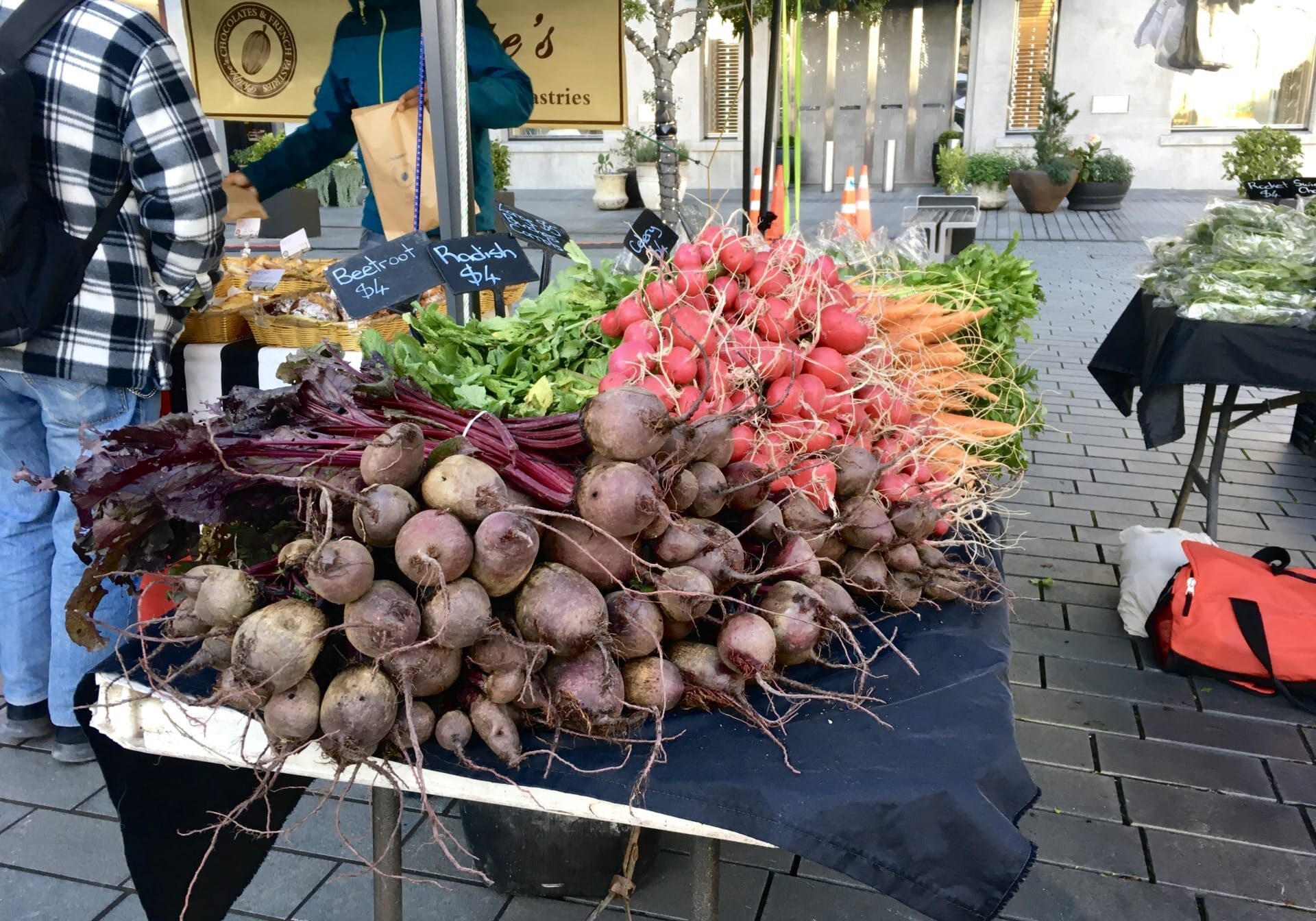 Root vegetables bundled and laid out on a table at a farmers market.