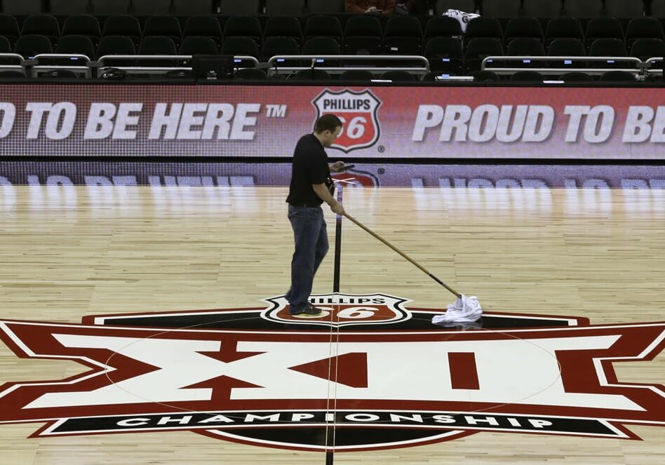 A worker cleans a basketball court floor