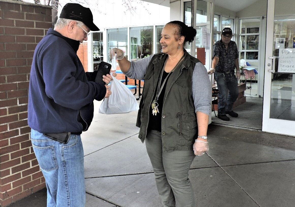 Staff member at Don Bosco Senior Center hands out a hot lunch.