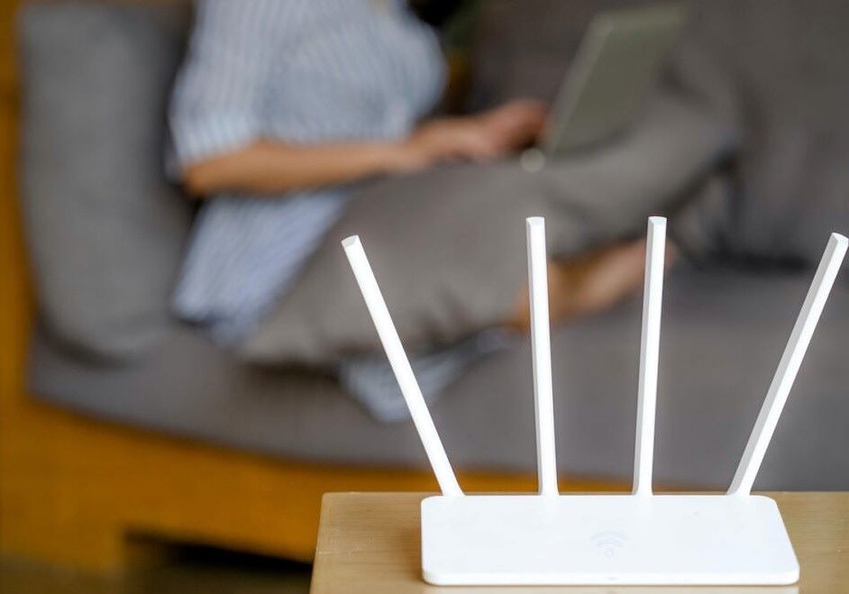 Wireless router and woman using a laptop in office.