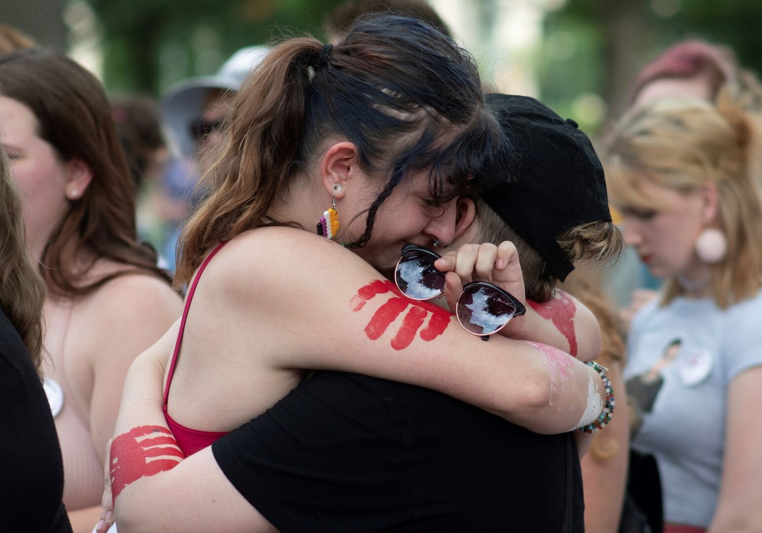 19-year-old Topekan Chole Easley, left, hugs her friends during a rally at the Statehouse Friday, June 24, 2022 in Topeka, Kansas.