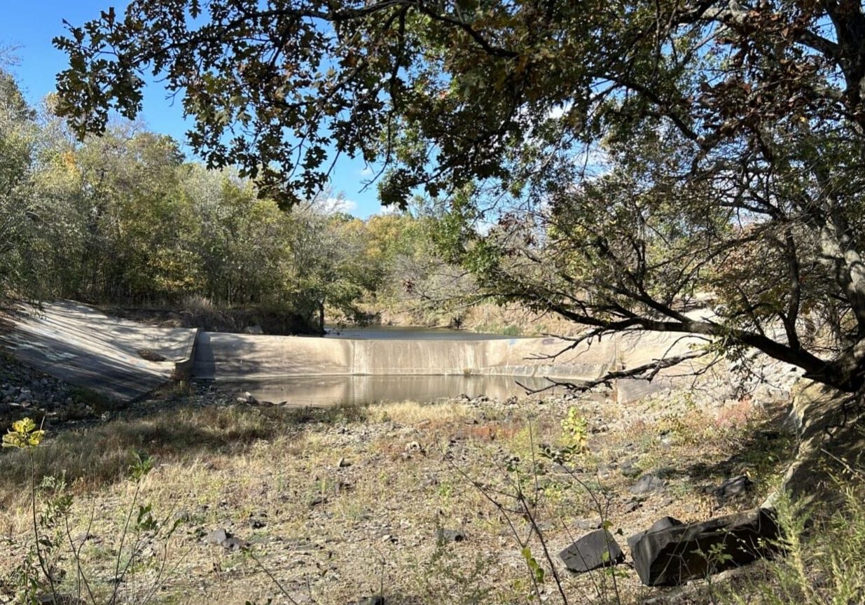 Water levels in the Little Caney River are so low that the river isn’t flowing over the dam, leaving the stream dry.