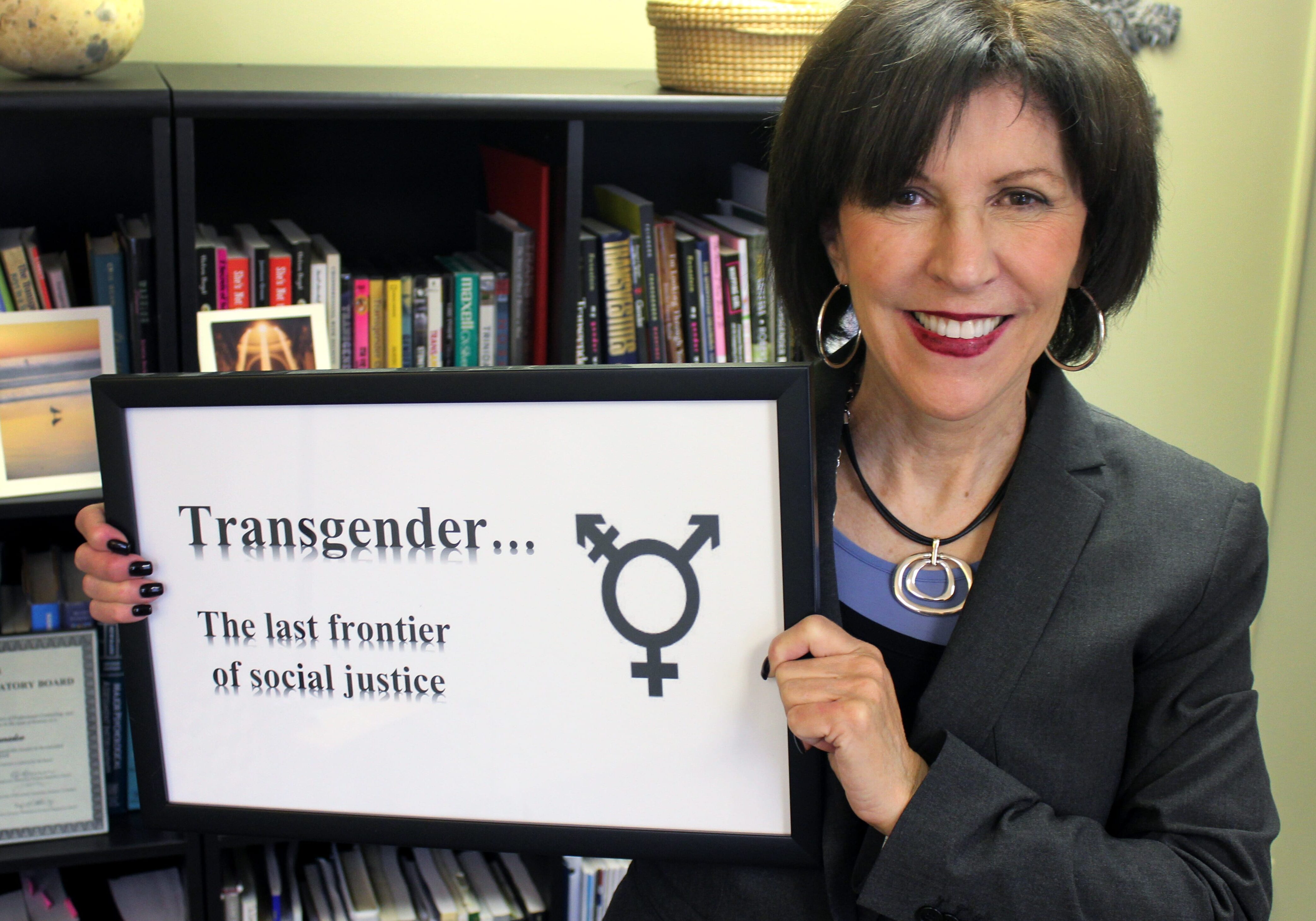 Image of woman holding a sign that says "Transgender... The last frontier of social justice"