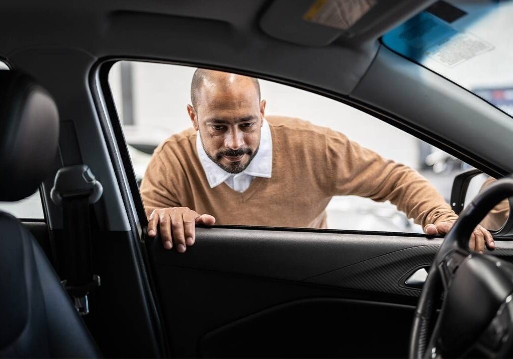 A man looks inside a new car.