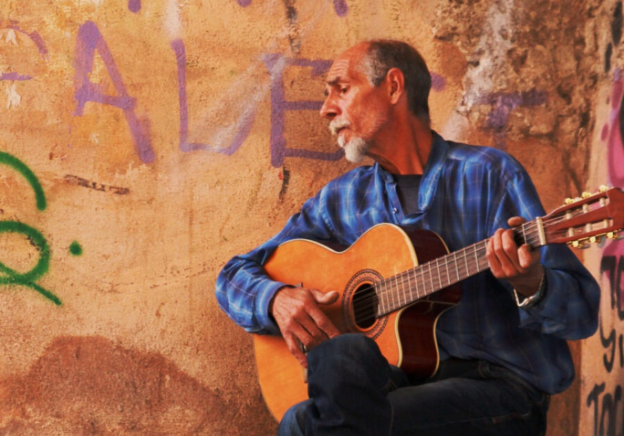 Man playing guitar on a stool